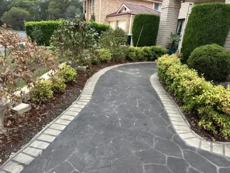 Curved driveway with a faded stencil pattern and light grey border, before concrete resurfacing